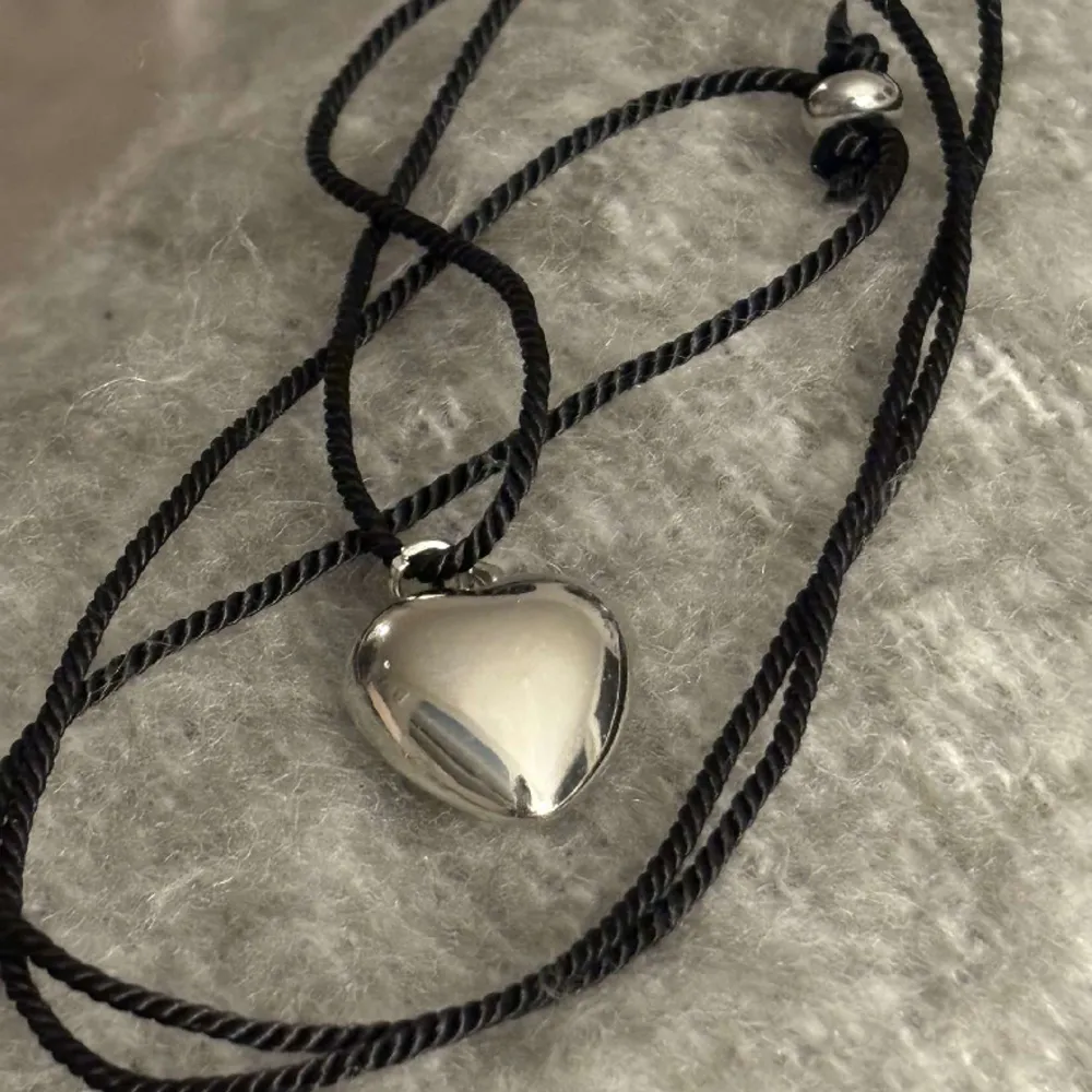 Säljer nu mitt finanlånga halsband. Med justerbart svart band med ett silverfärgat hjärta!💕. Accessoarer.