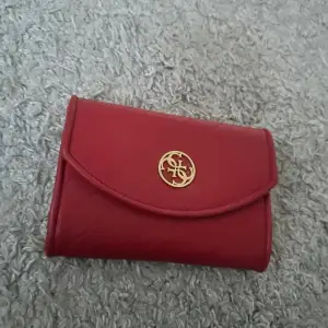 Röd plånbok från guess med band till så går att ha som väska, aldrig använt innan i fint skick 