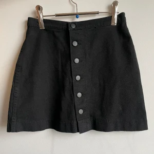 Svart minikjol från American Apparel  - Svart jeanskjol med knappar från American Apparel. 100% bomull. Bra skick!! 