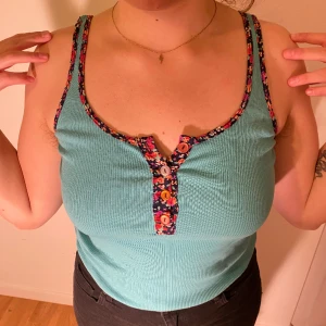 Linne m blomsterdetaljer - Ribbat vintagelinne i 60-talig turkos med knappar blomstersömmar