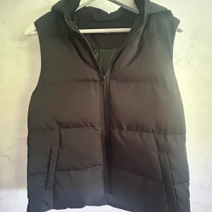 Svart Väst - Supersnygg svart väst med luva. Sitter otroligt bra och är varm och skön! Kommer tyvärr inte till användning 💕