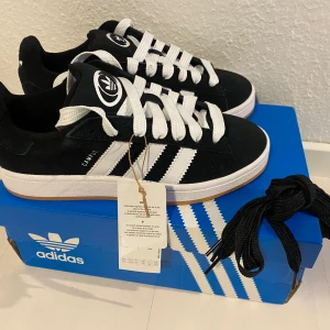 Nya svarta Adidas Campus 00s -storlek 37 1/3 - Adidas Originals Campus 00 s j 37 1/3. Svart. Core Black / Cloud White / Cloud White. Ingår både vita och svarta skosnören. Nya och oanvända. Kommer ej från någon massbeställning från utomlands. Köpta här i Sverige och därmed garanterat äkta.