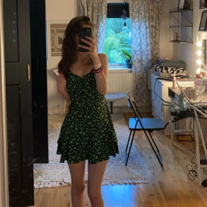 Gina tricot klänning  - Säljer denna fina utsålda gina tricot klänning i XS, svart med ungefär gröna växter på, då den inte kommer till användning ❤️ Man får knyta vid ryggen hur man vill ha den, sitter som en smäck ❤️