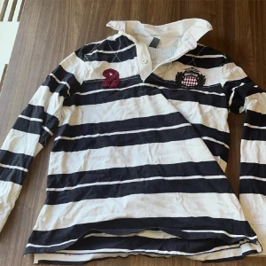 Rugby tröja - Säljer denna feta rugby tröja med patches på baksidan och en tvåa på baksidan. Nypris runt 1000kr. Inget hål eller skador. Hör av dig vid frågor