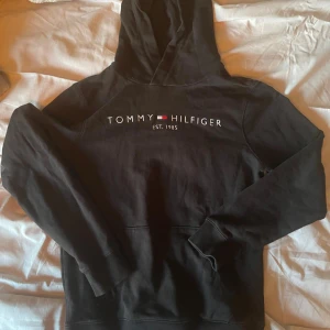 Tommy hilfiger hoodie svart - En riktigt najs Tommy hilfiger hoodie från kids brandstore storlek 164. Tröjan är sparsamt använd samt är inte riktigt bra skick säljer den pga av att jag växt ur den.  Ny pris: 799 kr Mitt pris: 300 kr
