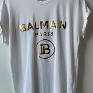 En vit t-shirt från Balmain köpt i en balmain butik i Dubai. Knappt anväd och i mycket bra skick men dock lagad. Det syns dock knappt när man har på sig tröjan. Prislapp och påse finns kvar! Den är köpt för ca 5600kr. Skriv för fler bilder. 