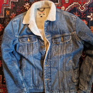 Lee Jacka - Mycket fint skick. Lee jeans jacka i Strl S. Mått: från axel till midja (eller jackan slut) omkring 64cm.  Jackan är begagnad men inte använd så mycket (inte sliten) Varmt foder på insidan. Unisex. Frakt ej inkluderat i pris. Kan mötas upp. 