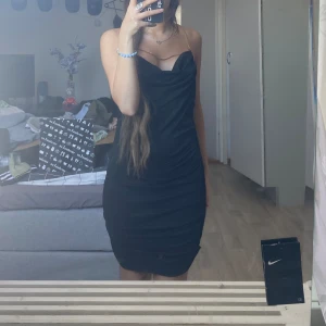 Festlig svartklänning - En svart festlig klänning med guld kedjor