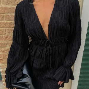 Strukturerad miniklänning  - En svart klänning med ett fint strukturerat/rynkat material. Den är från kollektionen Moa Mattson x NA-KD och plagget är helt oanvänt med lapp kvar. 