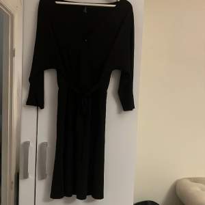 Gullig svart klänning med band i midjan och en viten ”osynlig” knapp vid skärningen 