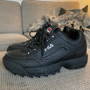 Svarta Fila Disruptors - Storlek 44.5. Sparsamt använda men lite smutsiga på ovansidan, inget som märks. Luddiga från strumpor på insidan men kan tas bort med luddborttagning. Pris kan absolut diskuteras!