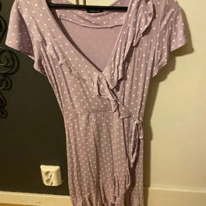 Klänning - Lila, kort klänning med vita prickar, volanger och knytning på sidan.💜 sydd vid urringningen och bra skick