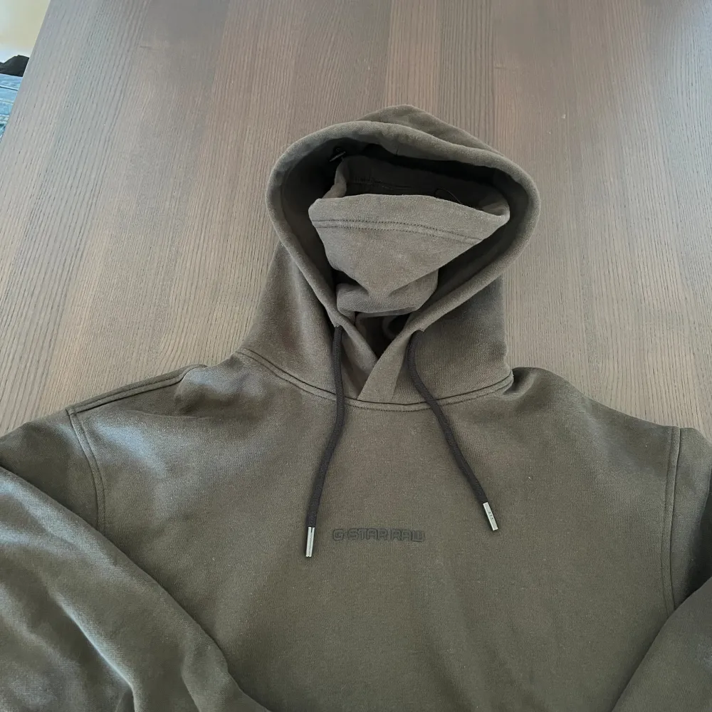 Unik G-Star hoodie med en inlagd balaklava/face cover (bild 3), perfekt för kylan.  Aldrig använd.  Cond: 10/10. Brun/grön färg.  Storlek: S  . Hoodies.