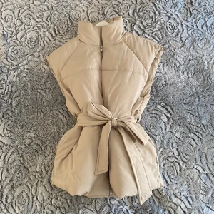 Väst från VILA - Vacker ljusbeige väst från VILA. Strl: 36 Stängs med dragkedja och band ✨ Finns fickor utan dragkedja