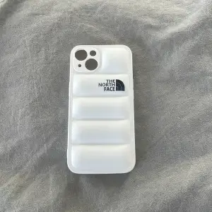 The North Face puffer mobilskal till iPhone 13 finns i både svart och vitt, skriv vilken färg du önskar 