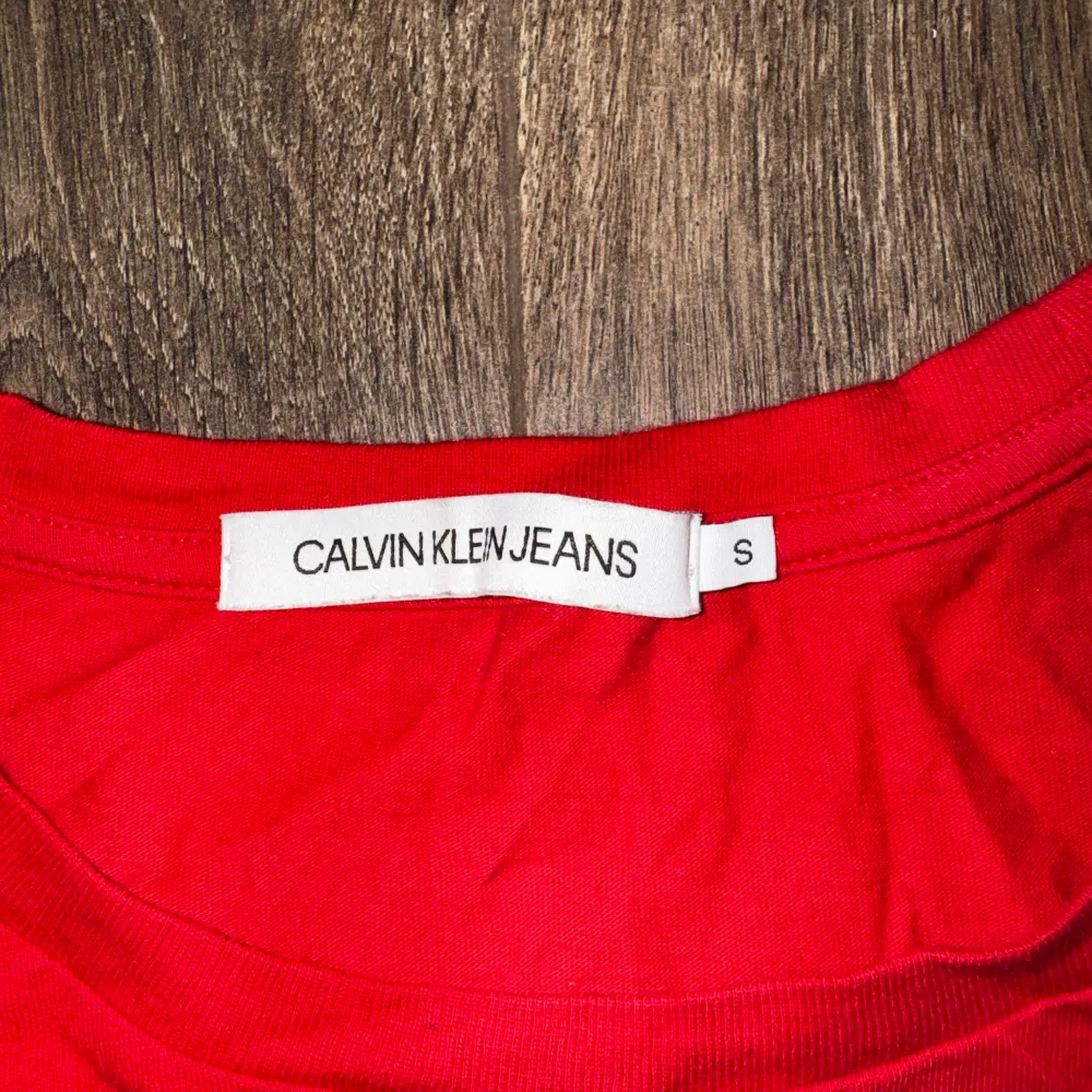 En röd Calvin Klein Jeans T-shirt med guld tryck. Knappt använd! Köpt för cirka 1 år sen. Priset kan diskuteras ☺️💕. T-shirts.
