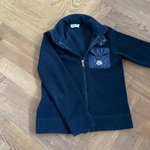 Fleecejacka Moncler - Storlek: 10 år, riktig snygg fleece som funkar både på vinter men även på sommarn, den är i mörkblå och är köpt i monclers hemsida. 