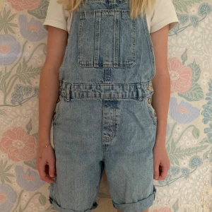 Blå hängsleshorts - Blåa jeanshängsleshorts. Hålfria, fläckfria och bra skick.