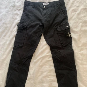 Calvin Klein cargo jeans - Ett par svarta Calvin Klein cargo jeans i bra skick. Storleken är S. Säljs för 200kr + frakt