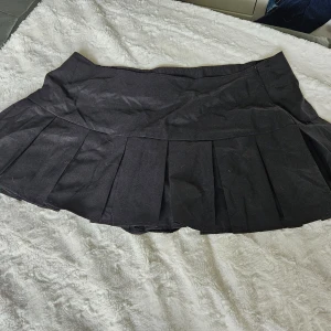 Svart veckad kjol  - Snygg svart kjol med veck. Kjolen har en dragkedja i sidan och inbyggda shorts. Köpt på shein . Står curve 1 xl. Lapp kvar. Katt finns I hemmet