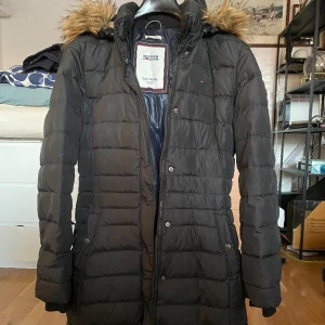 Tommy Hilfiger figursydd dunjacka - Jättefin Tommy Hilfiger dunkappa/anorak/ parkas. Använd men syns inte, jättefint skick  Lättvikt, otroligt värmande men jackan är så lätt att bära och även packa med sig.   Obs! Den är märkt stl M men liten i storleken så jag uppskattar den till S