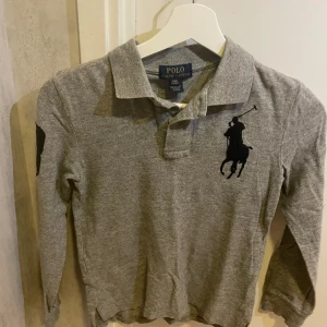 Grå polo piké  - Säljer denna gråa polo piké då jag växt ur den. Den är i fint skick och rätt så oanvänd.