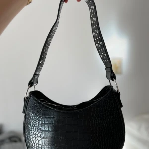 Svart axelväska - Svart axelväska i mycket gott skick. Kort axelband, går ej att förlänga.