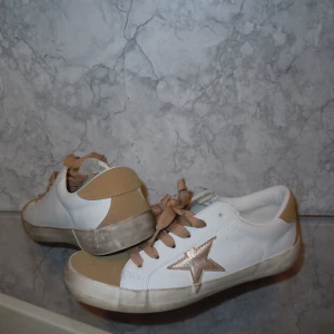 Skor 36 - Säljer grey goose liknande skor. Läder med guld detaljer och fejk mocha i guld.  Storlek 36