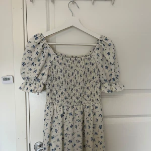 Vit lång klänning med blåa blommor på - Storlek Xs klänningen är från Shein andvändt några gånger,har en slit där nere. köpte den i början av maj 2023. 