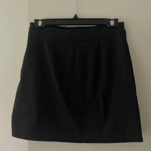 Svart kjol - Säljet denna enkla och stilrena svarta kjolen.  Kjolen har en rak passform och är i ett lite finare material. Köpt på Nakd och endast använd en gång. ✨🖤