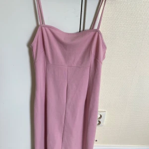 Rosa klänning med smala axelband - En elegant rosa klänning med smala axelband. Klänningen har en enkel och stilren design med en rak passform.
