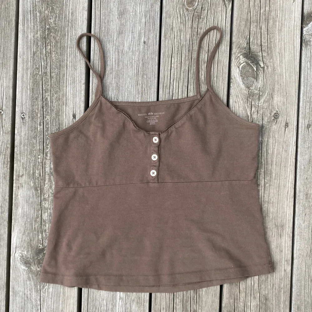 Jättegulligt linne från Brandy Melville. 💕 Brunt med liten spets upptill och tre knappar. Onesize (motsvarande small). Sparsamt använt, så i jättefint skick! . Toppar.