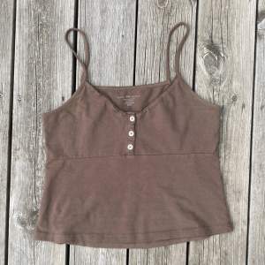 Jättegulligt linne från Brandy Melville. 💕 Brunt med liten spets upptill och tre knappar. Onesize (motsvarande small). Sparsamt använt, så i jättefint skick! 