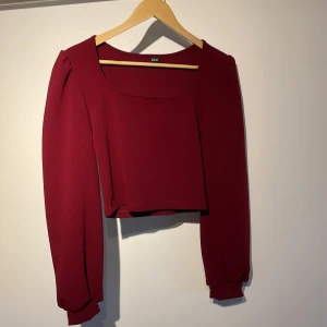 Magtröja  - En vinröd magtröja, står att det är storlek L men passar som S/M 