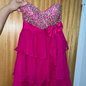 Kort glitter/volanger rosa festklänning  - 🌟 Fest klänning  🌟”Inbyggd” BH 🌟 Inga band/ offshoulder  🌟 Ganska Kort på mig och jag är 158 🌟Volanger  🌟Bekvämt  🌟Använd en gång  🌟 Bekväm