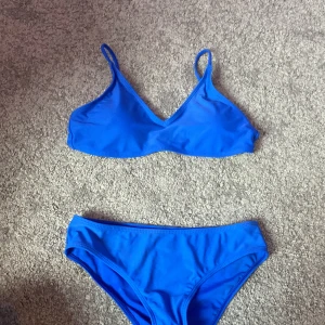 Blå bikini - En blå bikini med en enkel design. Överdelen har smala axelband och en V-ringning, medan underdelen är av klassisk modell.