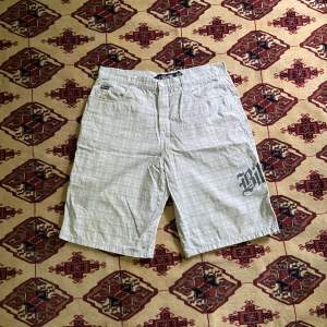 Billabong shorts, vita med gråa ränder och grå/silvrig text. Längd Ytterben 62cm. Innerben 31 cm. Midja 46.5 cm. Benöppning 34 cm. 