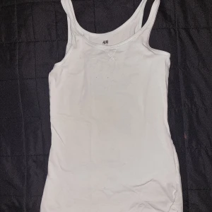 Vit linnetopp från H&M - En enkel och stilren Ljusgrön linnetopp från H&M. Toppen har smala axelband och är ärmlös, vilket gör den perfekt för varma sommardagar. stl 146/152