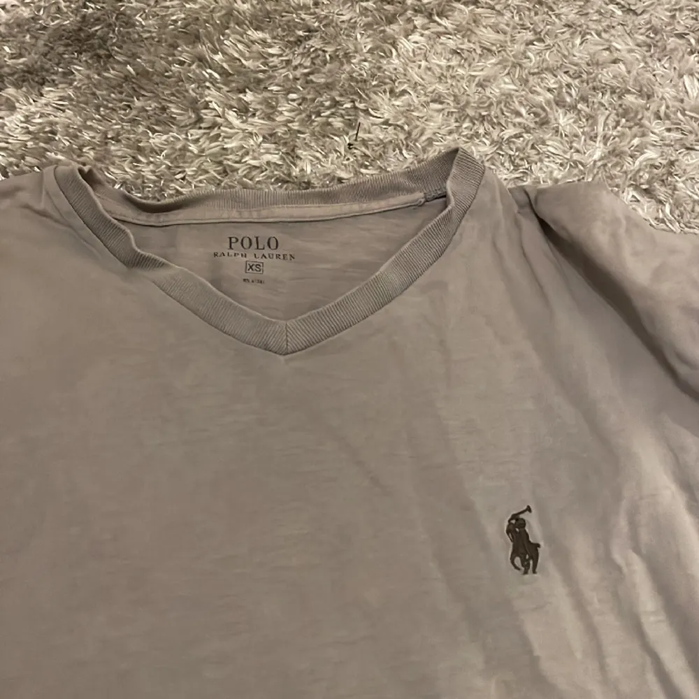 Jättefin grå ralph lauren t-short med en liten v-rigning. Strlek är xs, men funkar även för small. Tshirten är väl andvänd, därav priset.. T-shirts.