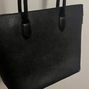 Svart väska - Svart skolväska jätte fin! 🖤🖤🖤🖤🖤 Från sida till sida längst upp 44 cm. Från sida till sida längst ner 32 cm. Lodrätt: 31 cm (ej räknat med band)