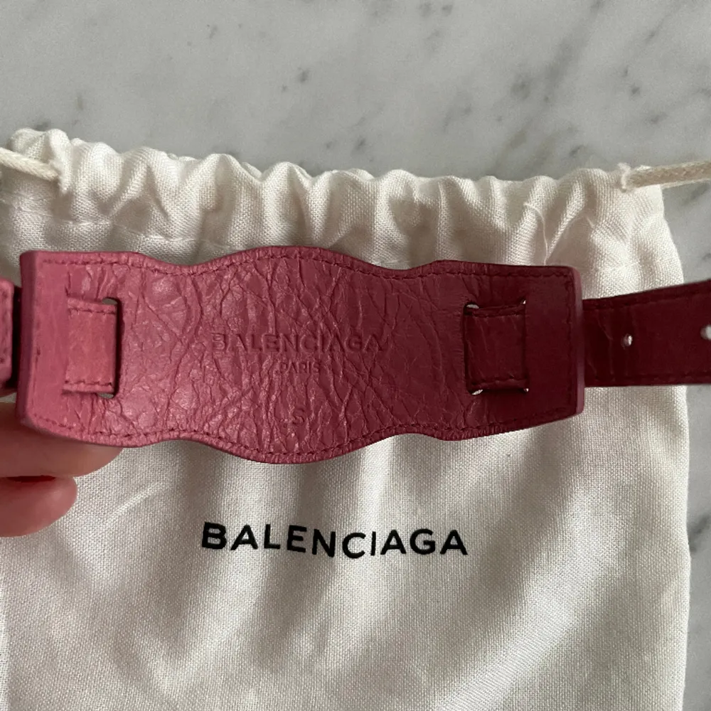 Rosa armband med guld detaljer från Balenciaga i nyskick. Inköpt från Vestire Collective (aldrig använd) så finns både äkthetsbevis & kvitto. Storlek S (20cm). . Accessoarer.