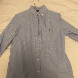 Klassisk Ralph Lauren skjorta i färgen blå. Storleken är 14-16 eller L (barnstorlek). Super stilig och passar alla!