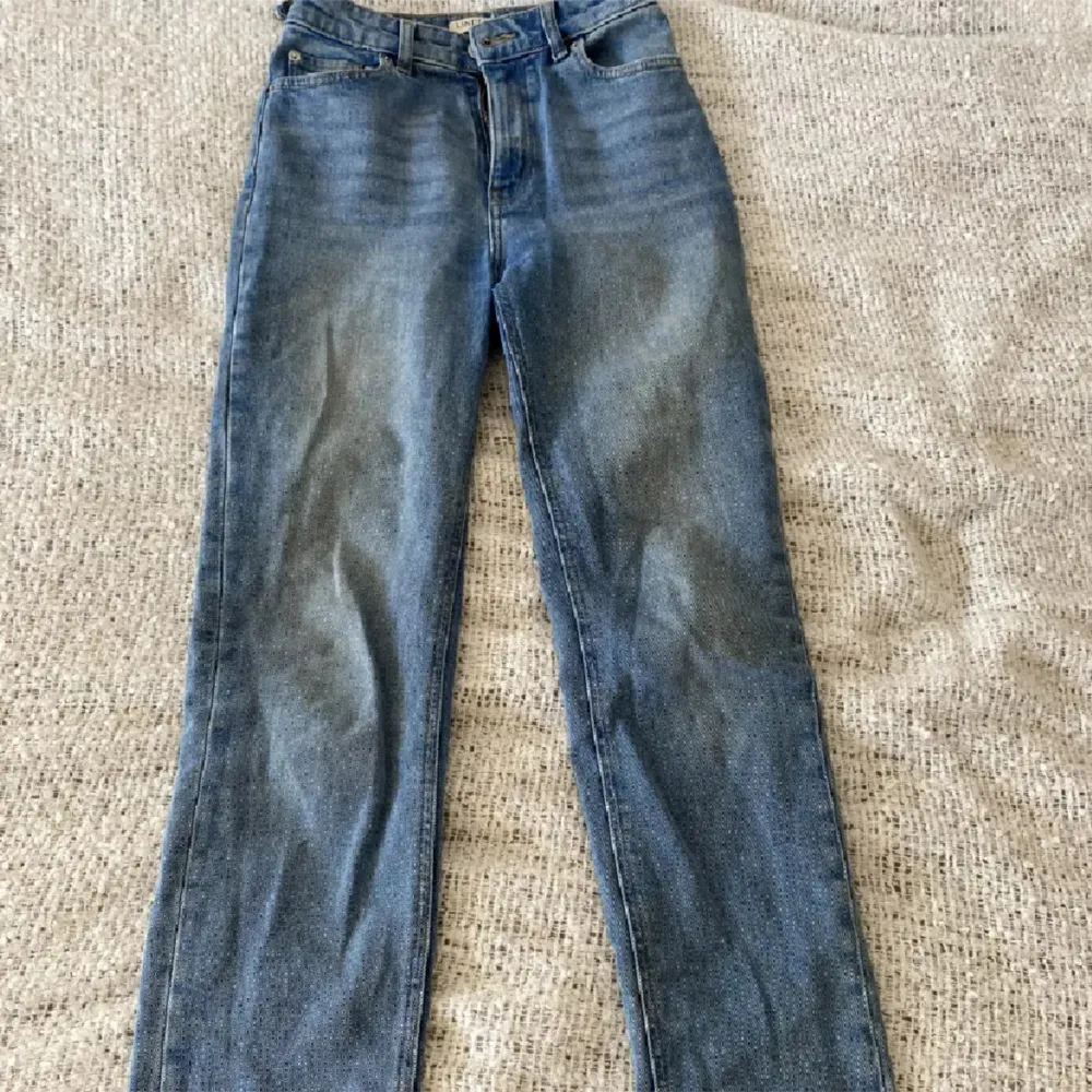 Ett par blå jeansbyxor i storlek xs för dam. Byxorna har en klassisk design med raka ben och en normal passform. De är tillverkade av jeansmaterial och har en dragkedja och knappar framtill.. Jeans & Byxor.