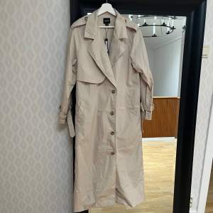 Beige trenchcoat i storlek small, helt oanvänd med lappar kvar. 