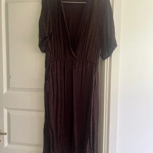 Mörk klänning - En brun klänning med V-ringning och korta ärmar. Klänningen har en elastisk midja och ett mönster som liknar leopard. Har fickor. oanvänd med saknar prislapp.