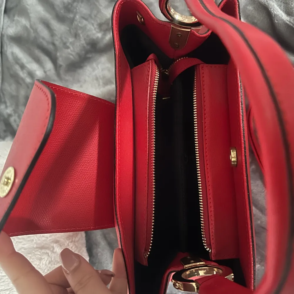 En fin röd väska i läder köpt i Italien oanvänd med band och prislapp, stor o rymlig med fack i!. Väskor.