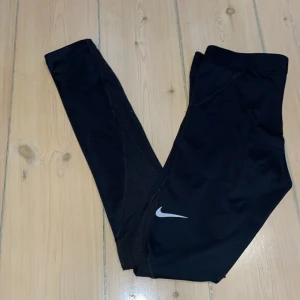 Nike träningstights - Träningstights från Nike i storlek S. Litet slitage/”hål” vid ena sidan av benet (bild 3) men annars i fint skick! Pris kan diskuteras 