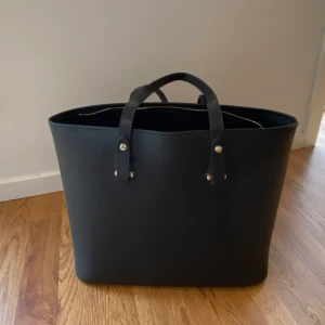 Väska hm - Säljer denna fina väska från hm som inte längre säljs. Inte använd så mycket, ganska bra skick. Höjd:30 cm,bredd:40 cm,djup:15 cm (ca). Får därför plats med en dator med mycket plats över. 3 fack inuti varav en går att stänga, precis som hela väskan.