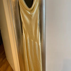 Rygglös Ljusgul Criss kors klänning i stlXS  - Jätte fin ljus gul lång klänning med djup rygg och dragkedja på sidan i stl XS endast använd en gång så i nyskick. 