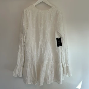 Klänning NA-KD  - Vit klänning med blommor på i storlek 36 från NAKD. Aldrig använd och har lappen kvar. Perfekt till studenten eller sommaren!☺️